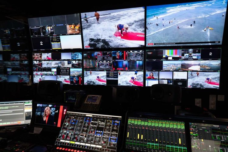 Kontrollpanel for tv-regi og mange skjermer med forskjellige bilder. Rommet er mørkt, men skjermene lyser opp.