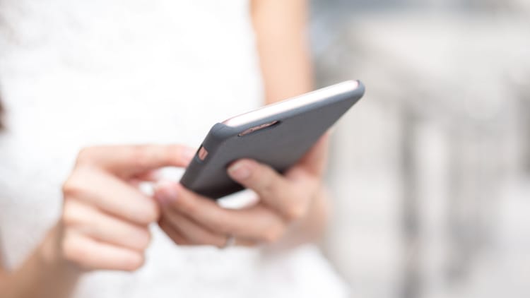 En person holder en mobil foran seg og bruker den høyre hånden til å navigere rundt på skjermen.