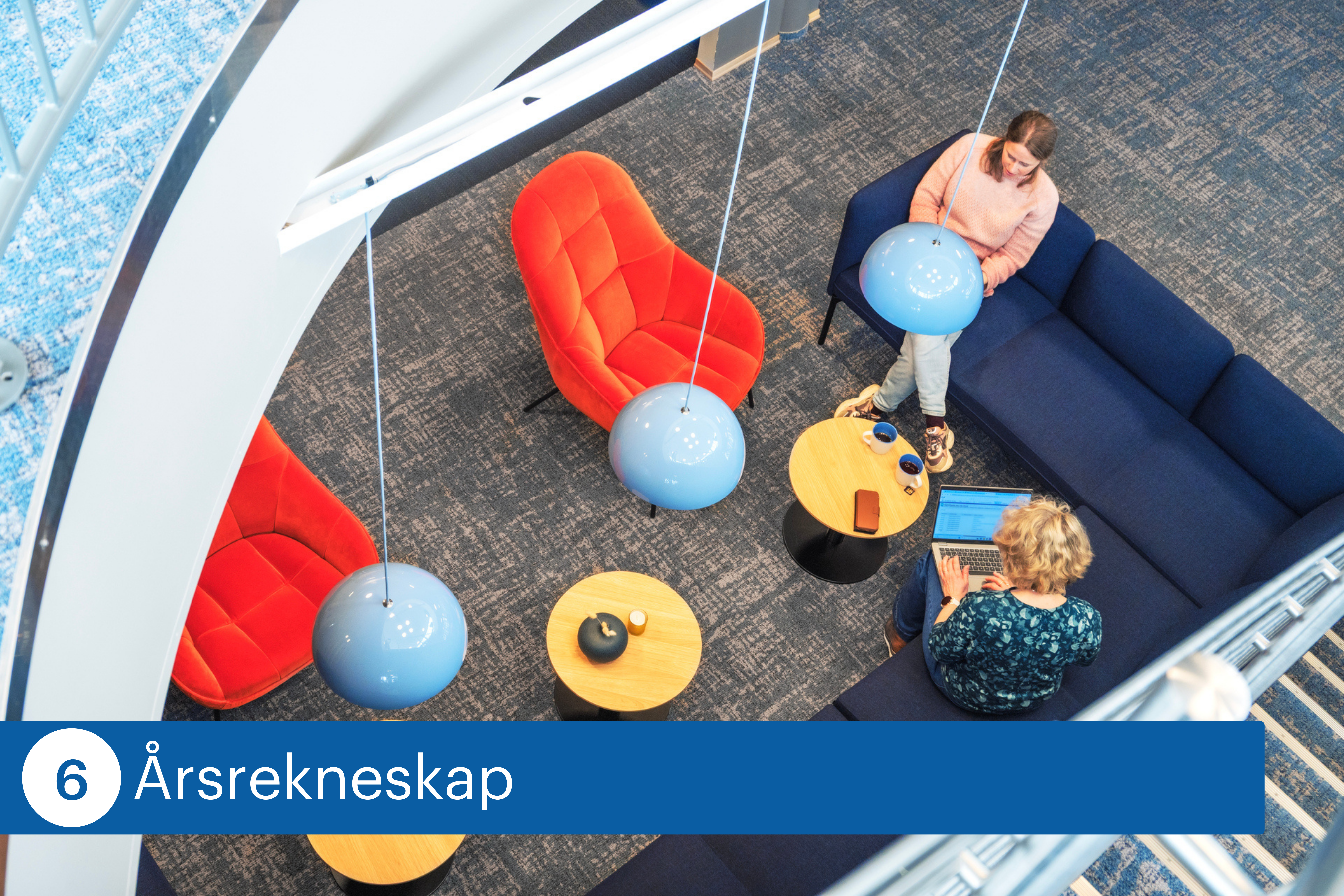 To personer sitter i et uformelt sitteomr&aring;de med sofa og stoler. Den ene bruker en b&aelig;rbar PC ved et bord, mens den andre sitter med en kopp. Rommet har moderne m&oslash;bler og hengende lamper.