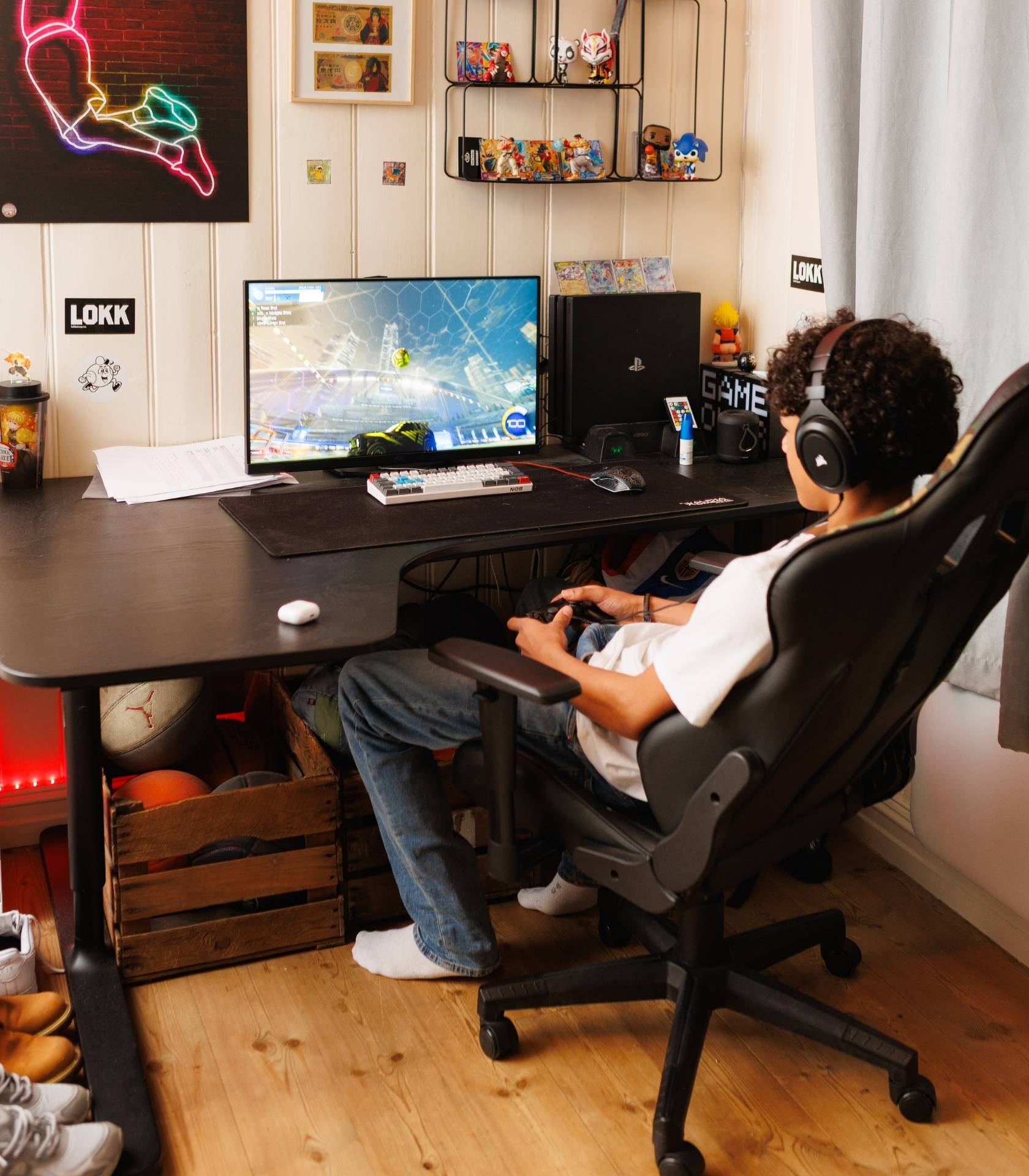 Ung person sitter ved en gaming-PC med hodetelefoner og h&aring;ndkontroll og spiller et bilbasert videospill.